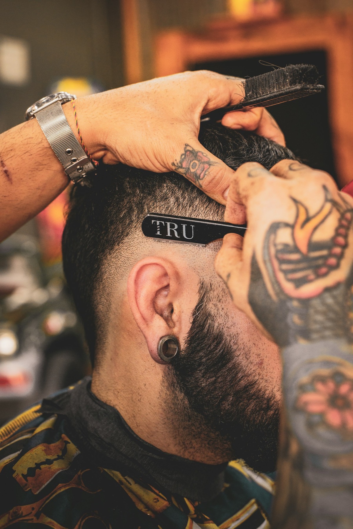 Barbier en action, machine en main, lumière chaude